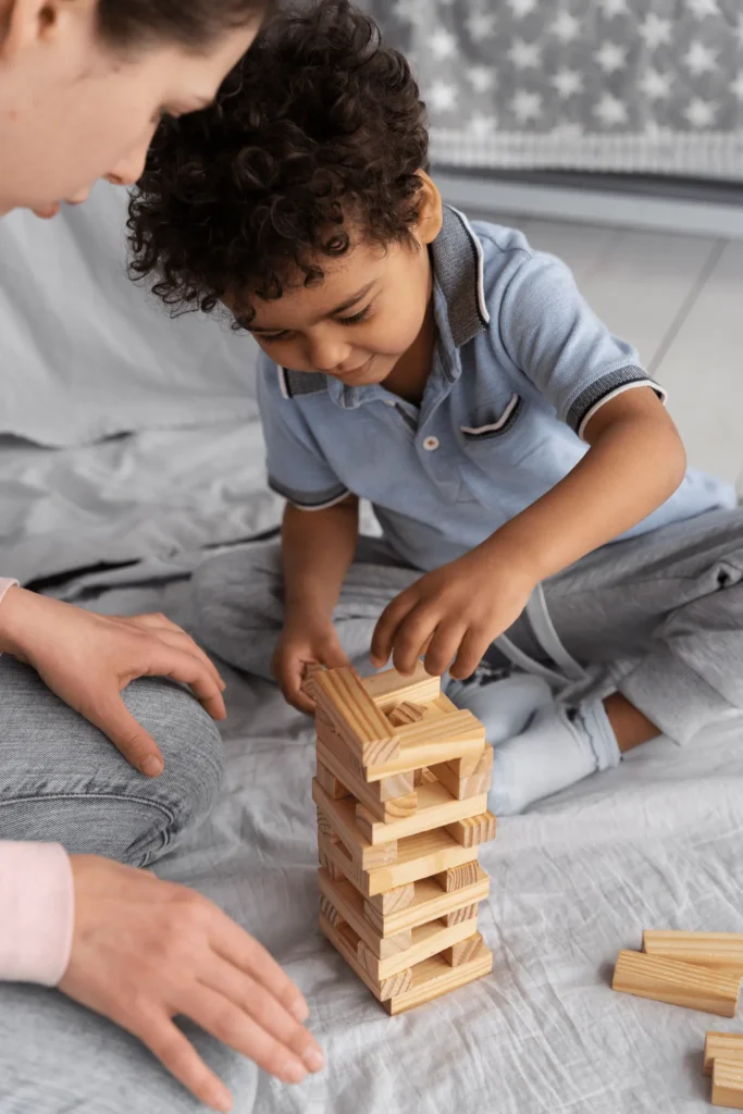 Menino pequeno encaixa blocos de madeira, desenvolvendo coordenação motora e concentração.